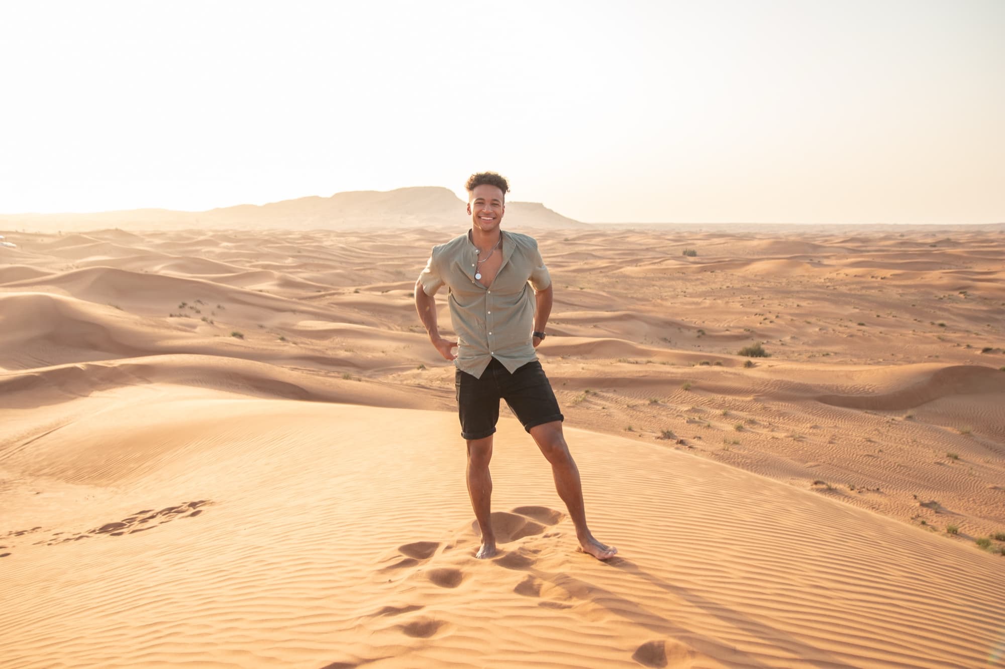 Quest standing on desert dunes at sunset